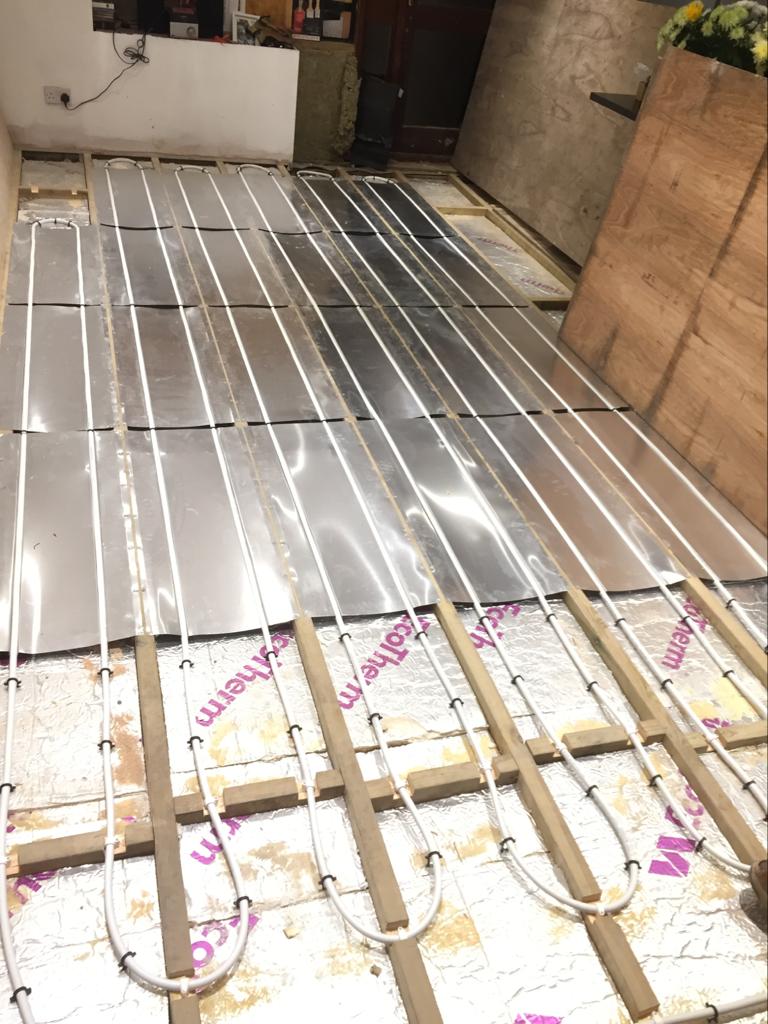 Underfloor Heating installation pipes going through wooden joists